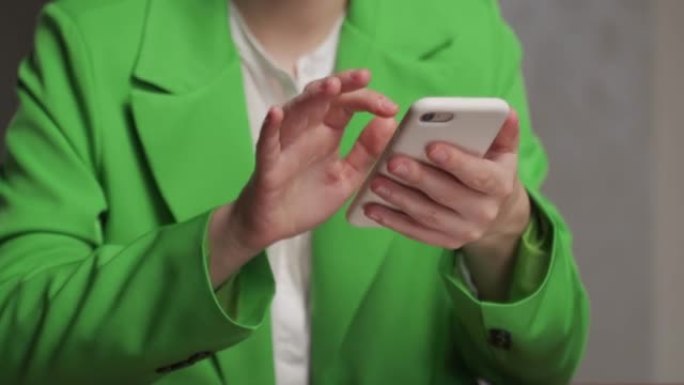 穿着经典绿色夹克的年轻女子通过电话检查邮件
