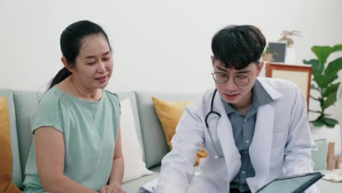 年轻的亚洲男性医生向老年患者解释药物。