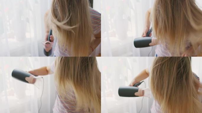 一名年轻女子用电吹风吹干长发。美容和护发的概念