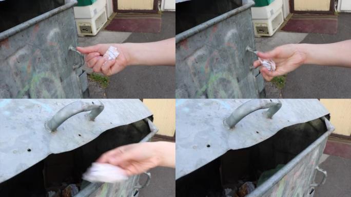将皱巴巴的纸垃圾扔进旧的垃圾容器中-年轻的女性手部动作象征着对回收和环境的关注