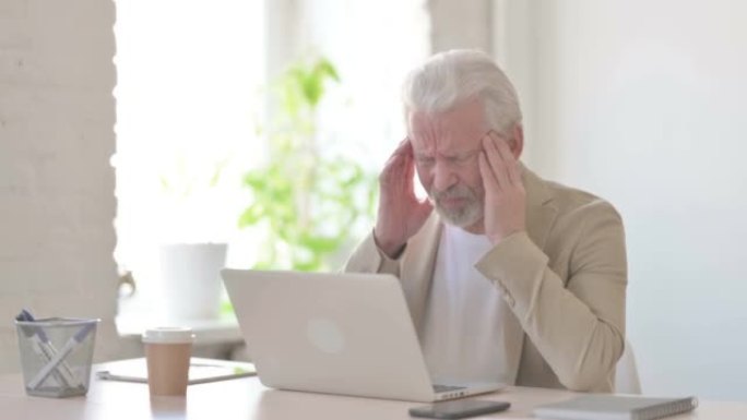 老人在笔记本电脑上工作时头疼