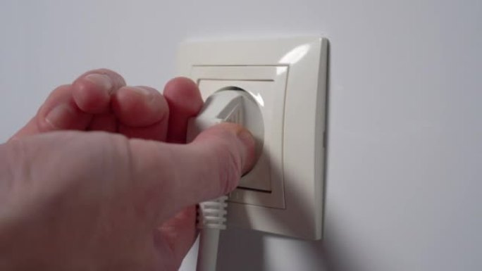 人从家用电插座上拔下电插头。节省昂贵的电力