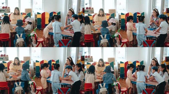 2名亚洲华人蒙台梭利幼儿教师在教室里向学生展示玩具积木