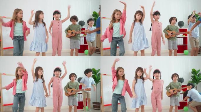 一群男孩和女孩站在幼儿园学校的教室前，跳舞。弹吉他的男孩。学习、享受、教育、游戏理念。感到快乐和有趣