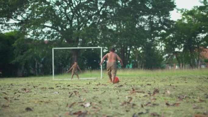 小男孩练习点球。亚洲男孩朋友在乡村的夏日晴天在绿草地上踢足球。概念友谊和世界杯的比赛之路。