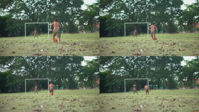 小男孩练习点球。亚洲男孩朋友在乡村的夏日晴天在绿草地上踢足球。概念友谊和世界杯的比赛之路。