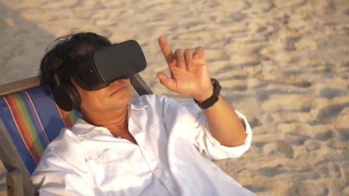 亚洲男子在海滩上放松时戴着虚拟现实眼镜。