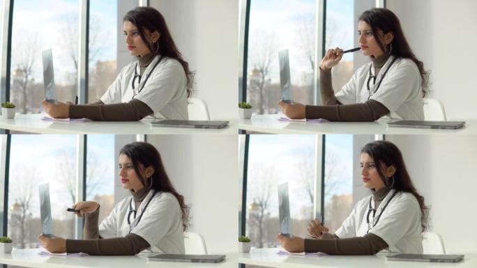 在诊所实习的年轻印度医学生。穿着白大褂的女医生拿着听诊器检查x光片并做记录