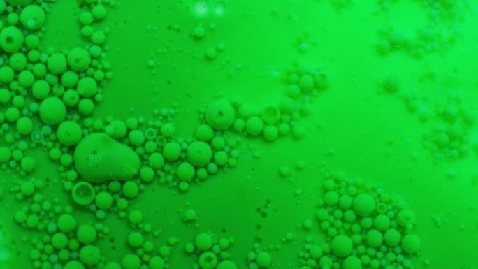 两种不溶性介质。不寻常的抽象绿色背景与许多小滴。平稳的运动。失重和表面张力。实验实验室