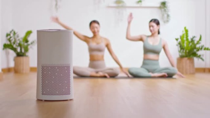 舒适的白色客厅空气净化器，用于过滤和清洁去除灰尘PM2.5 HEPA在家与女性在背景中锻炼瑜伽，为新