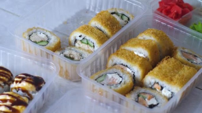 用筷子将桌子上的寿司盘放在运输容器中。从东方餐厅运送新鲜寿司。传统日本料理烤寿司。