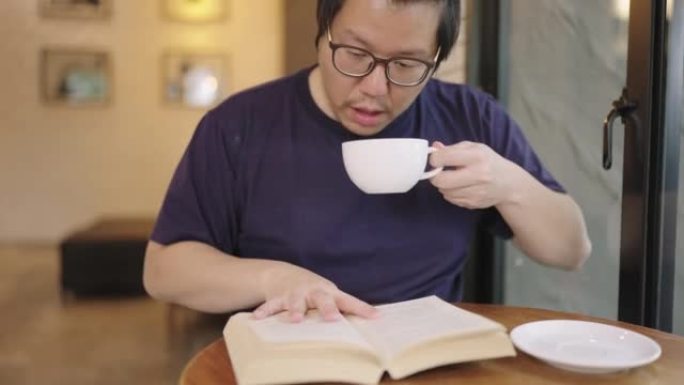 年轻人早上喝咖啡，在咖啡馆看书。