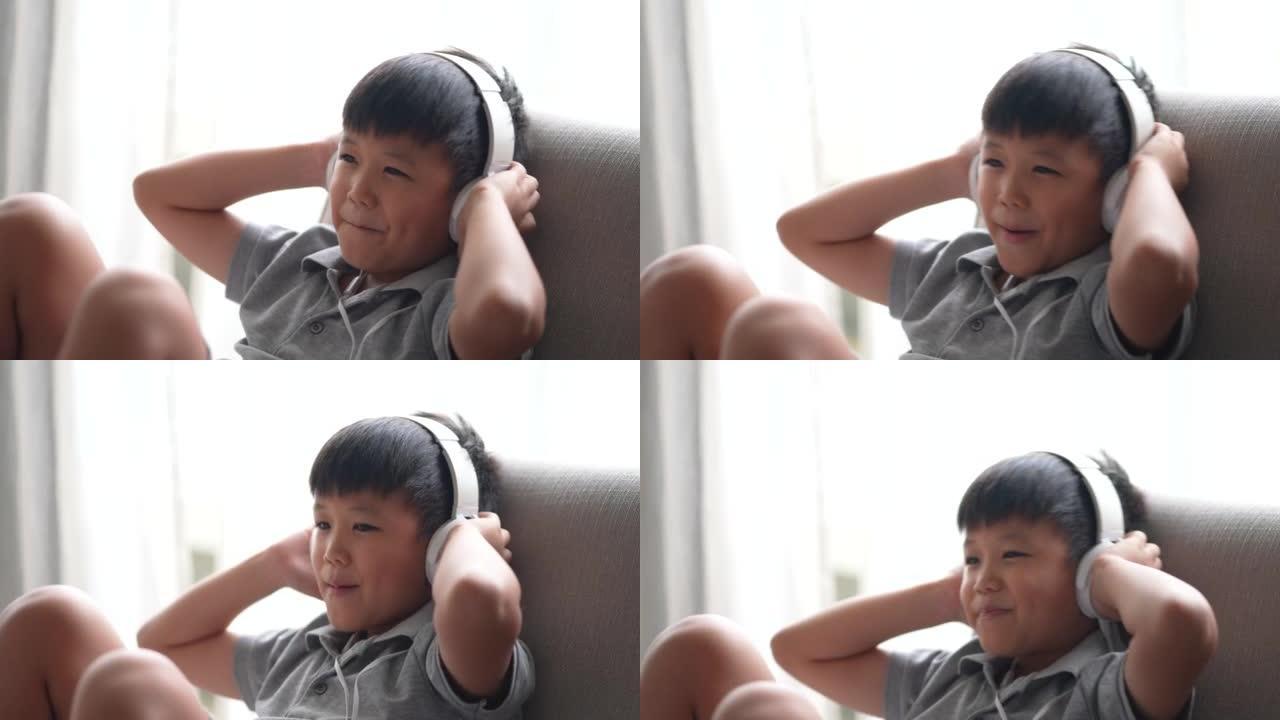 亚洲男孩在沙发上用耳机愉快地听音乐