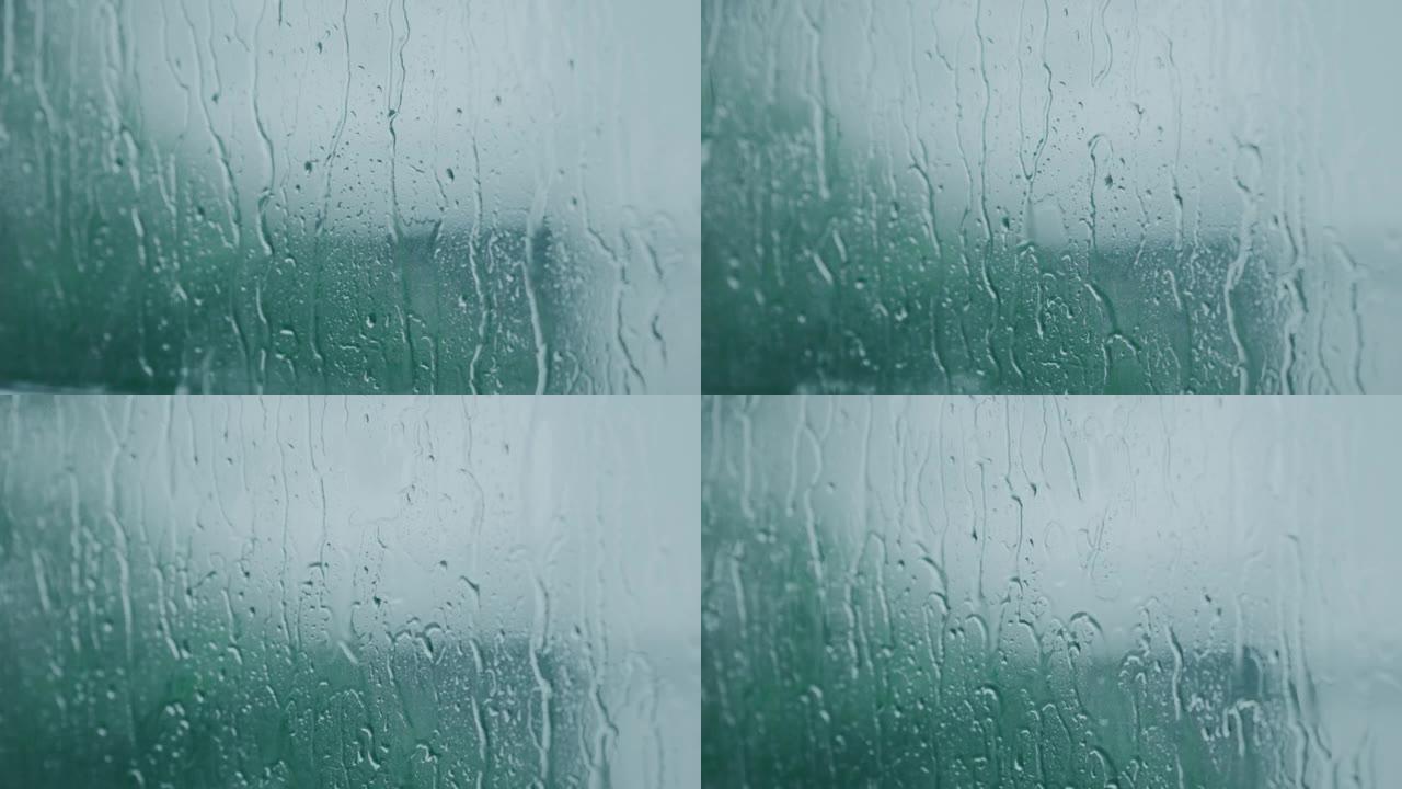 雨水形成的水滴流入窗户上的玻璃。4k，慢动作。