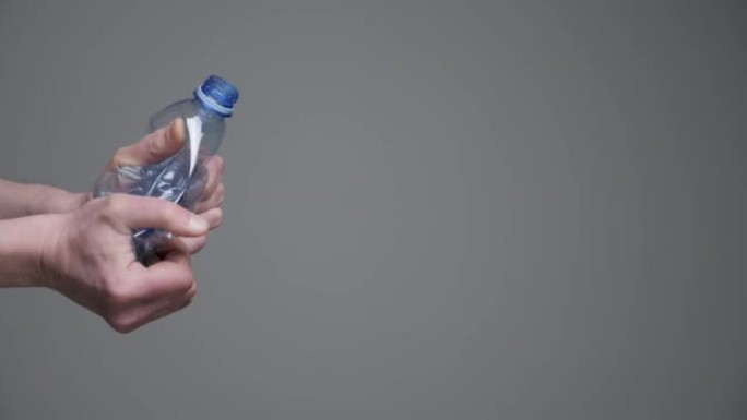 手扭瓶皱巴巴的塑料减少概念。压碎的瓶装水。调整大小。用过的宠物。抓手压碎塑料瓶回收pet塑料减少废料