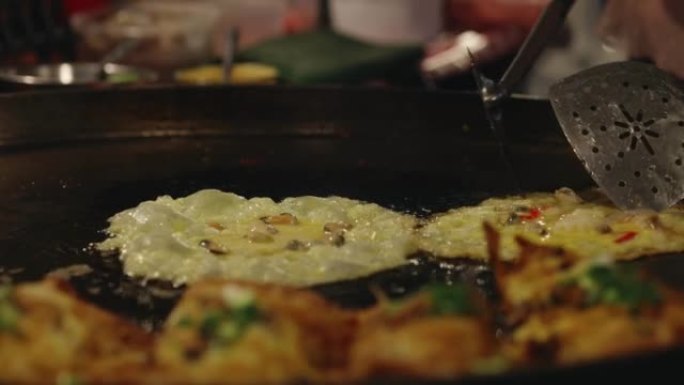 特写厨师使用巨型平底锅炸蛤蜊，泰国美味的街头美食。