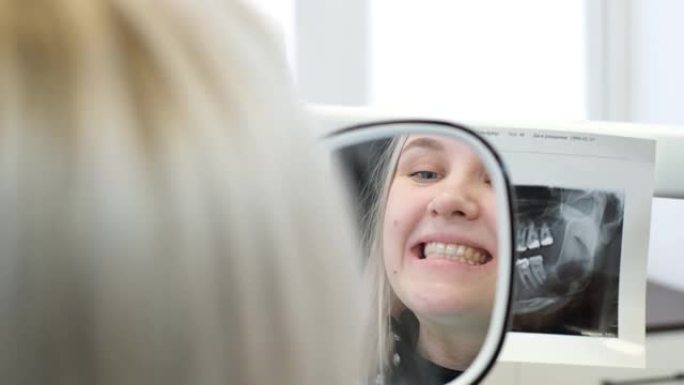 一个满意的病人看着牙镜里愈合的牙齿。