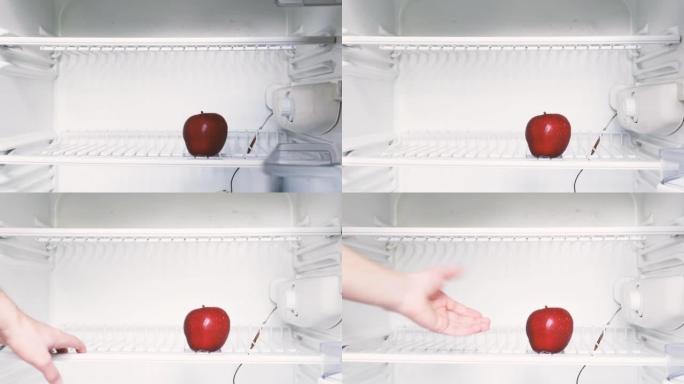 一个人的手打开一个空冰箱，拿了一个红苹果。概念性4k原始视频。经济危机、粮食短缺、贫困的想法。