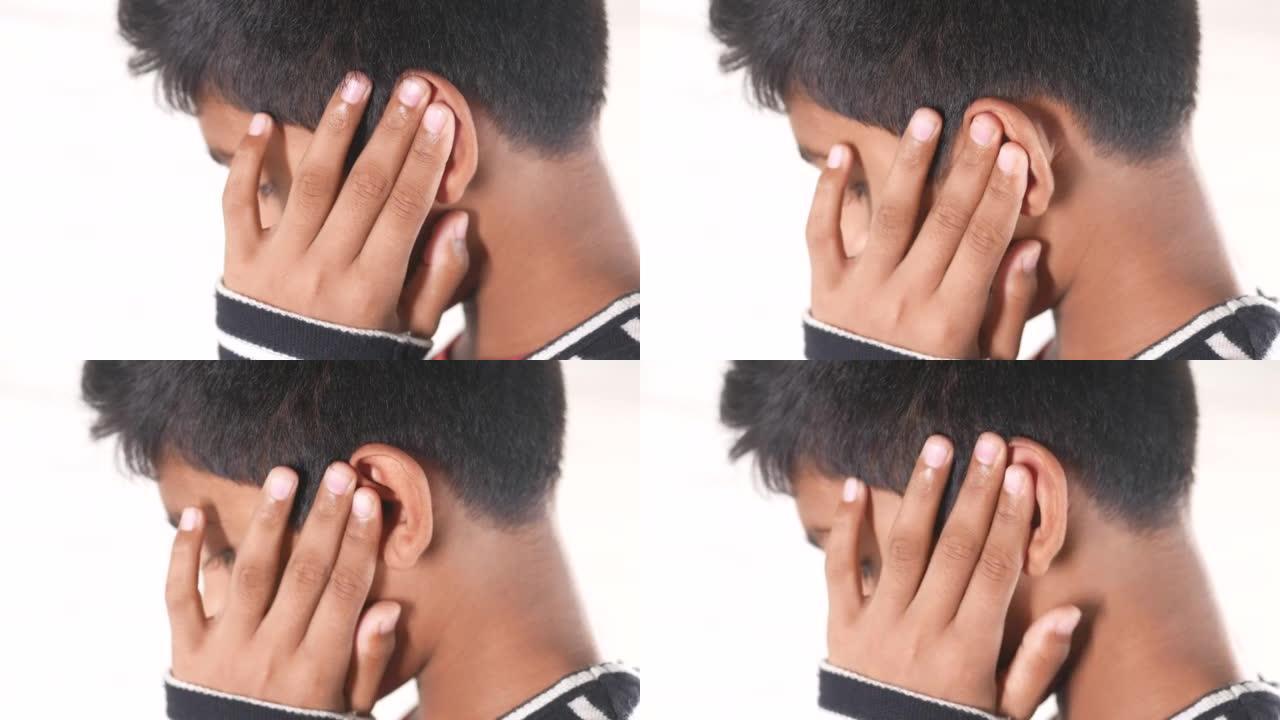十几岁的男孩耳朵疼痛触摸他痛苦的耳朵，