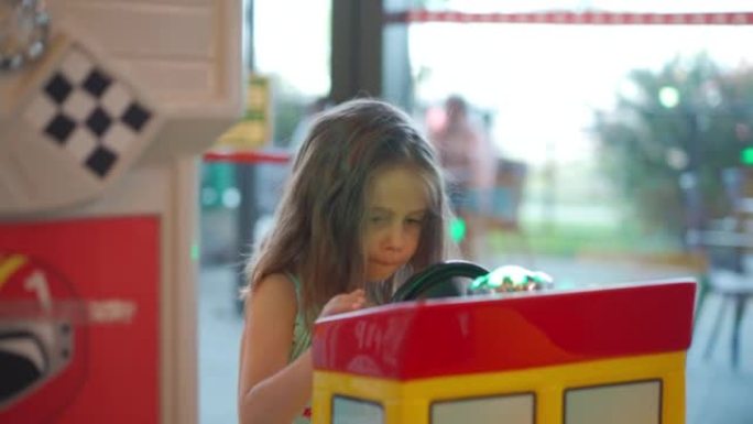 小高加索女孩坐在购物中心儿童娱乐角的车轮玩具电动车上