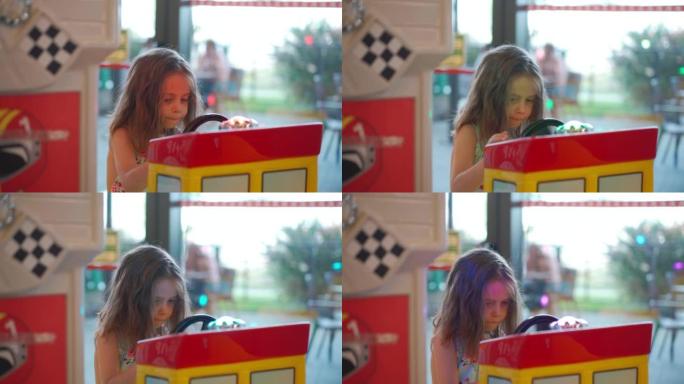 小高加索女孩坐在购物中心儿童娱乐角的车轮玩具电动车上