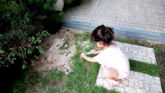 小女孩试着在地上种草，在草地上倒些土，晚上在家玩耍。