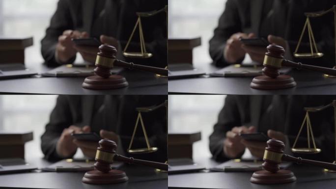 在线法律顾问概念法官的锤子和秤放在后台回答智能手机消息的律师旁边。