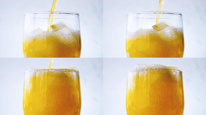 橙色苏打水倒入带有白色墙壁背景上的冰块特写的玻璃杯中。用流行橙色苏打水溢出湿玻璃。具有速度斜坡效果的