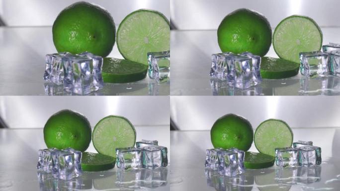绿色柠檬是空白的，有一个切块，显示了柑橘皮的内部。透明玻璃反射柠檬和湿水的阴影，使其清新，冰增加冷却