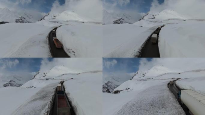 格鲁吉亚古达里美丽雪山的鸟瞰图。卡车车队沿着山路行驶