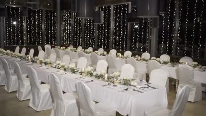 优雅桌在大厅设置白色主题婚宴。宽镜头，视点相机