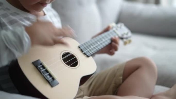 亚洲男孩在家练习吉他和四弦琴。学习和幸福的概念