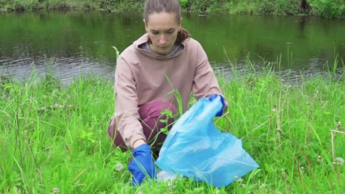 一名环保志愿者年轻女子从河岸收集旧塑料垃圾