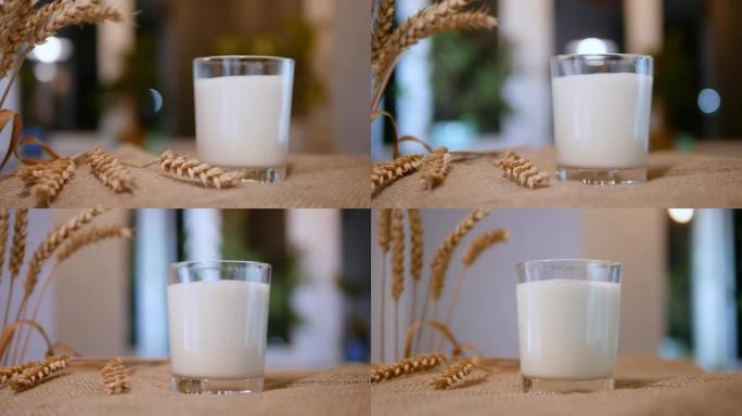 带有乡村背景的透明玻璃杯的牛奶，稻草袋上的玻璃杯中的天然牛奶饮料