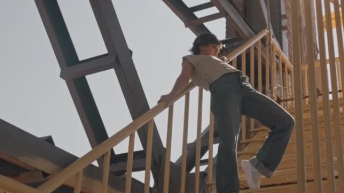 年轻女子在建筑工地的黄色楼梯上跳舞