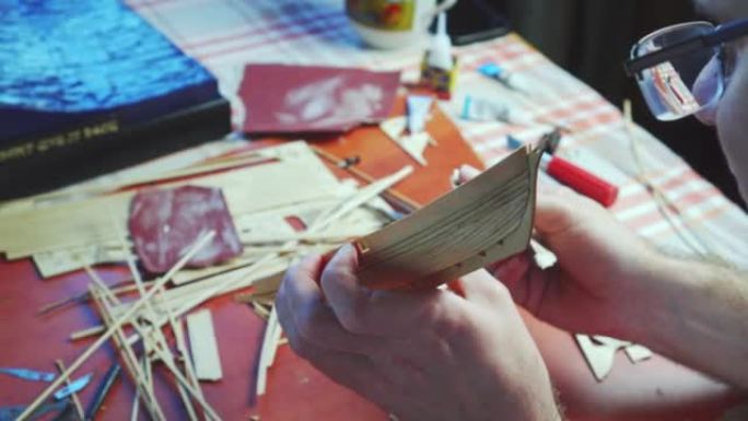 人手调整船模的胶合板细节，在砂纸上打磨。建造玩具船、工艺品的过程。