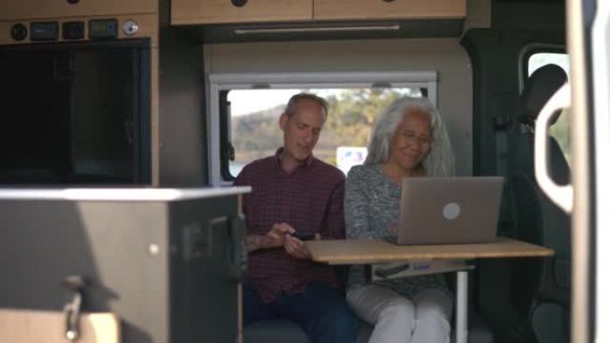 退休夫妇在定制露营车中使用笔记本电脑