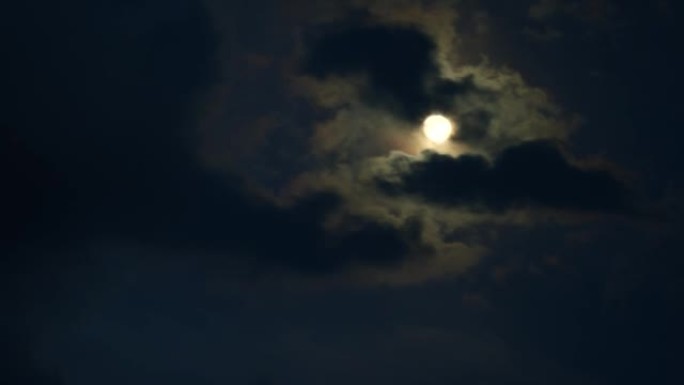 月亮在夜空中黑暗的戏剧性云层上的延时