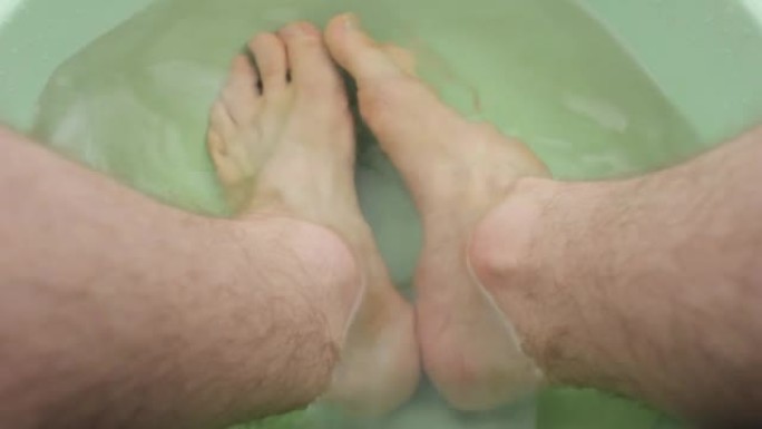 足浴。一个人把脚浸入盆中。足部治疗。