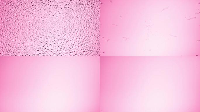 湿玻璃上的水滴在粉红色背景上被吹走