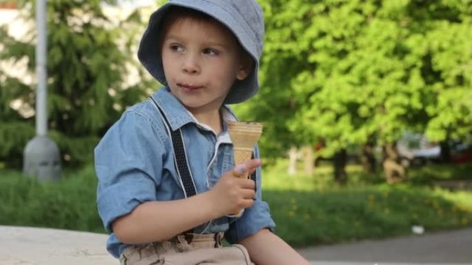 可爱的蹒跚学步的孩子，在公园的户外吃冰淇淋，他周围的春天的花朵，花园里的喷泉
