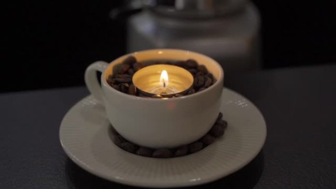 在一杯咖啡豆和燃烧的蜡烛中