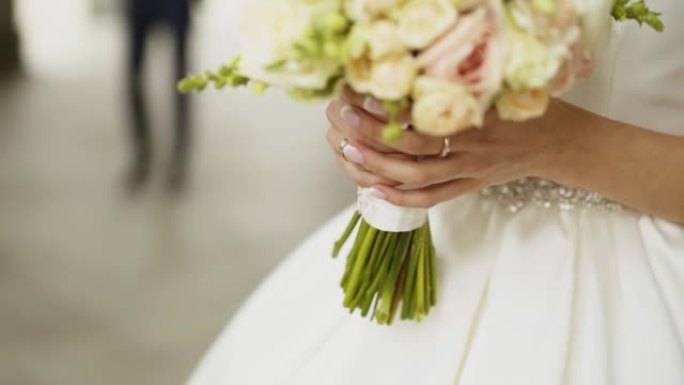 新娘手里拿着一束白玫瑰。男人的影子接近女孩
