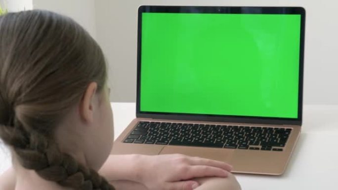 回到学校。女学生在绿屏笔记本电脑前在线学习