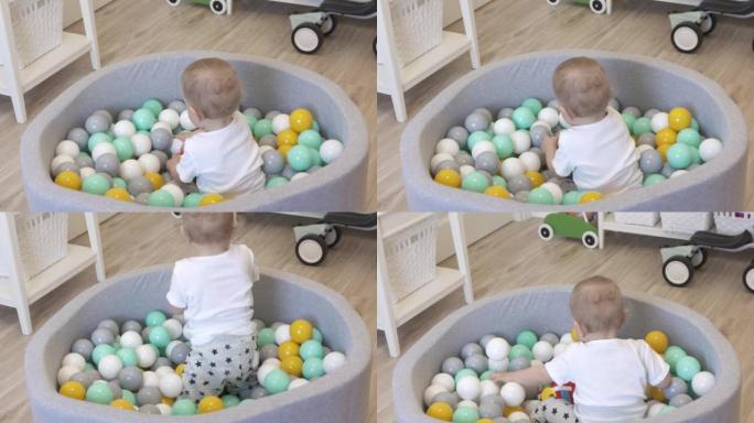 孩子在家打球。快乐的孩子在软球坑池中，有五颜六色的球供幼儿使用，高加索男婴在家里玩得很开心。。高质量