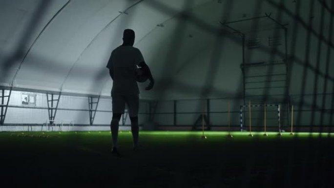 精疲力竭的足球运动员在训练后独自在室内的足球场上行走，史诗般的慢动作射击