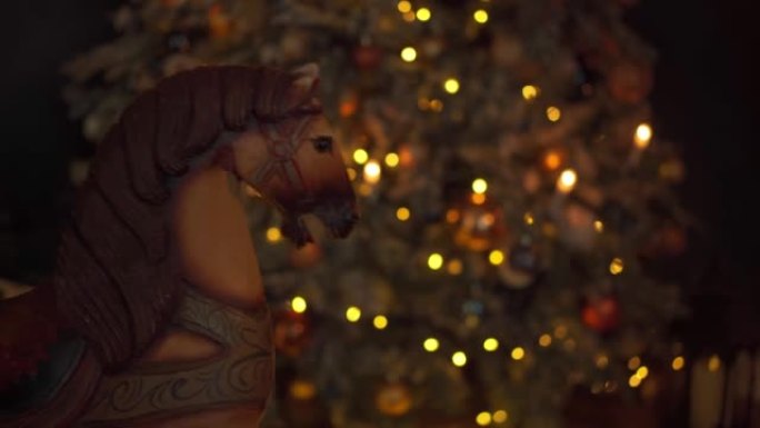 圣诞气氛。老式木制马椅秋千在圣诞节晚上摇摆，背景是圣诞树。舒适的假日氛围