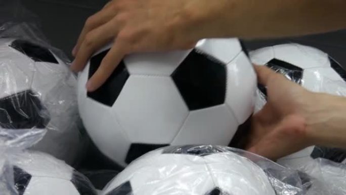 体育用品部门许多足球的特写镜头和一名男性手拿一个