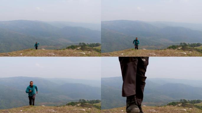 男子在山顶上奔跑，从平面角度有迷雾的山怒背景