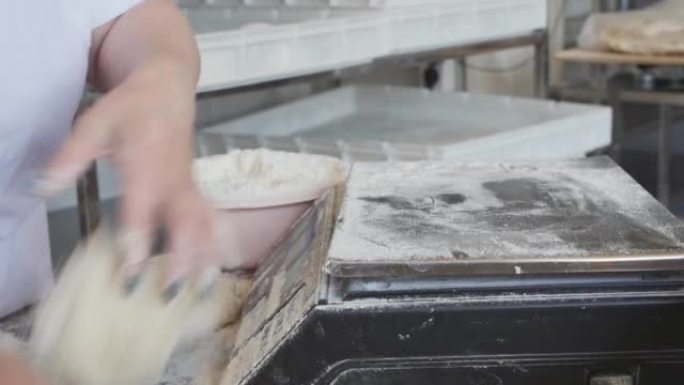 女面包师的手在数字秤上称重部分生面团，用于烘烤相同的面包